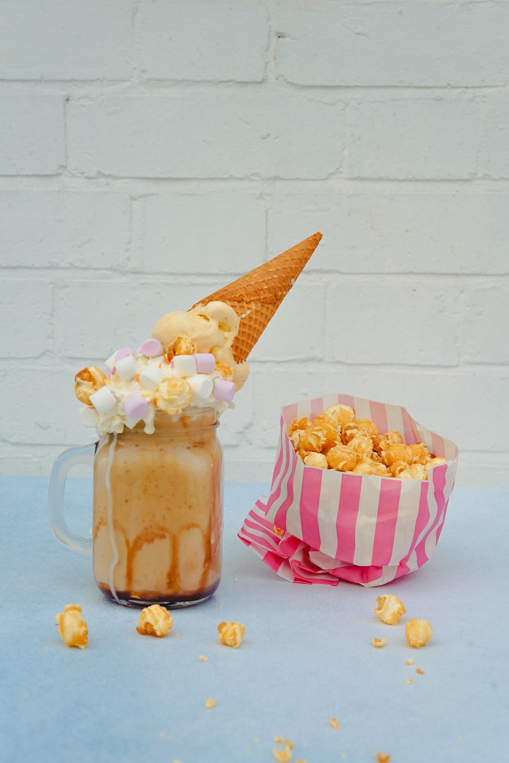 Eis im Glas mit Marshmallow und Waffel und einer Packung Popcorn