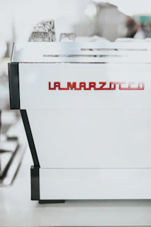 Happy customer holding a freshly brewed cup of espresso next to their La Marzocco machine.