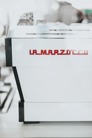 Happy customer holding a freshly brewed cup of espresso next to their La Marzocco machine.