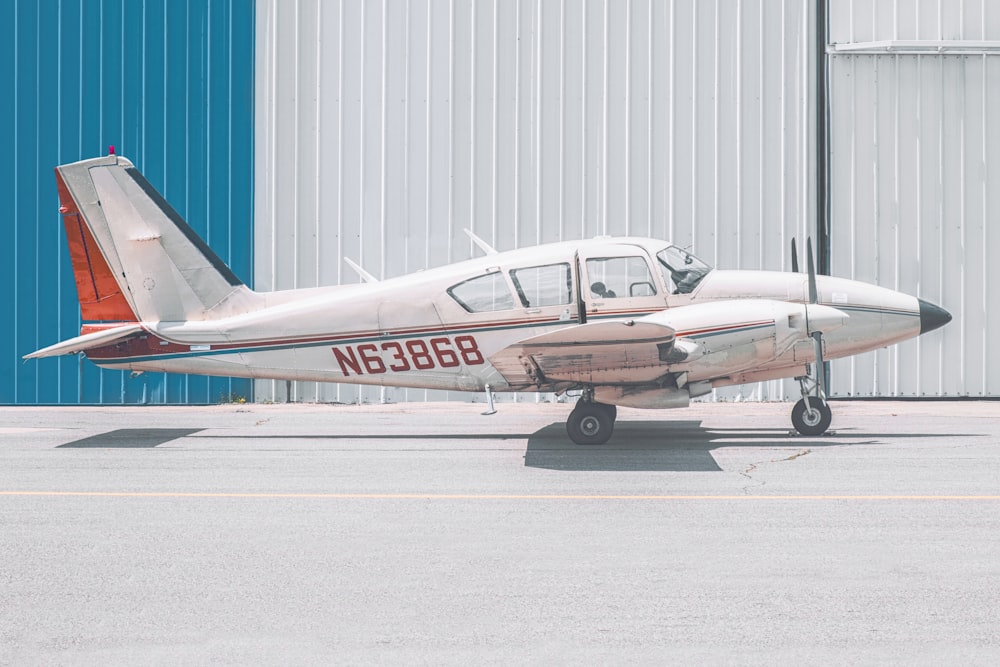 weiß-orangefarbenes Flugzeug N63868 tagsüber in der Nähe des Gebäudes geparkt