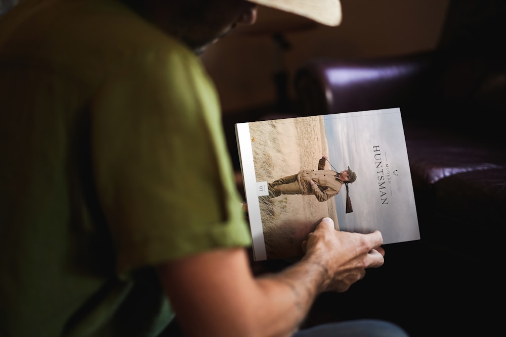 person holding book while sitting near sofa chair