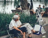 two men sitting on bench beside portrait paintings