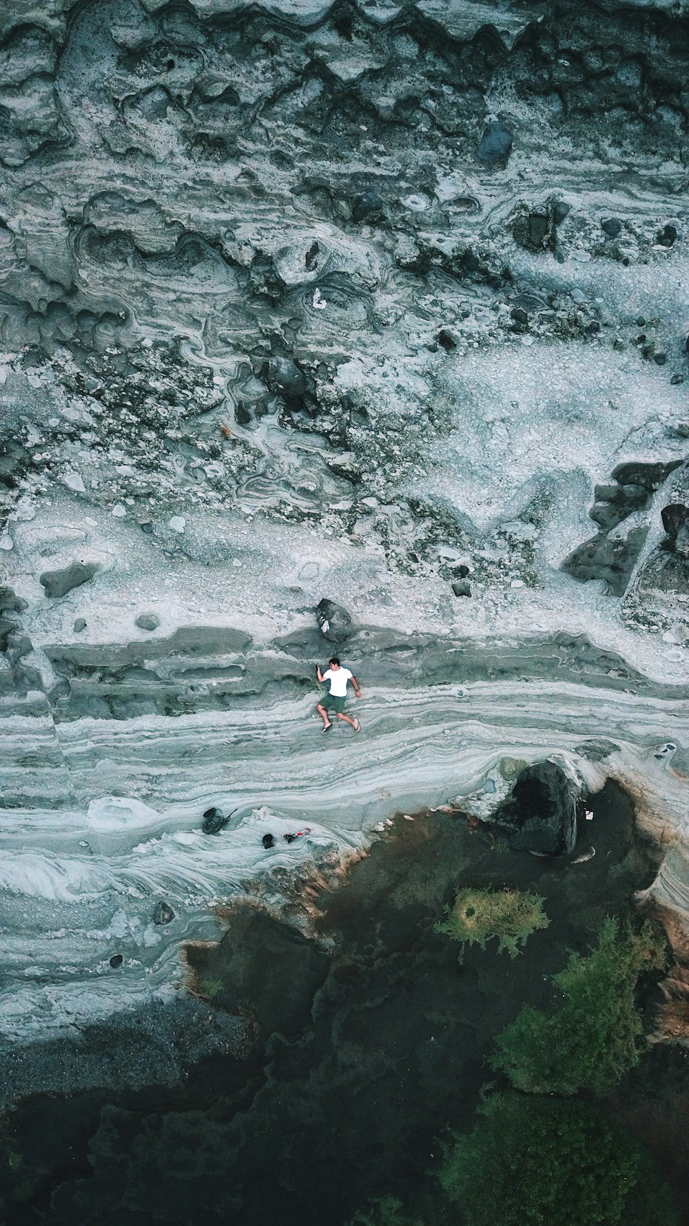 man laying on grey and white rock surface during daytime