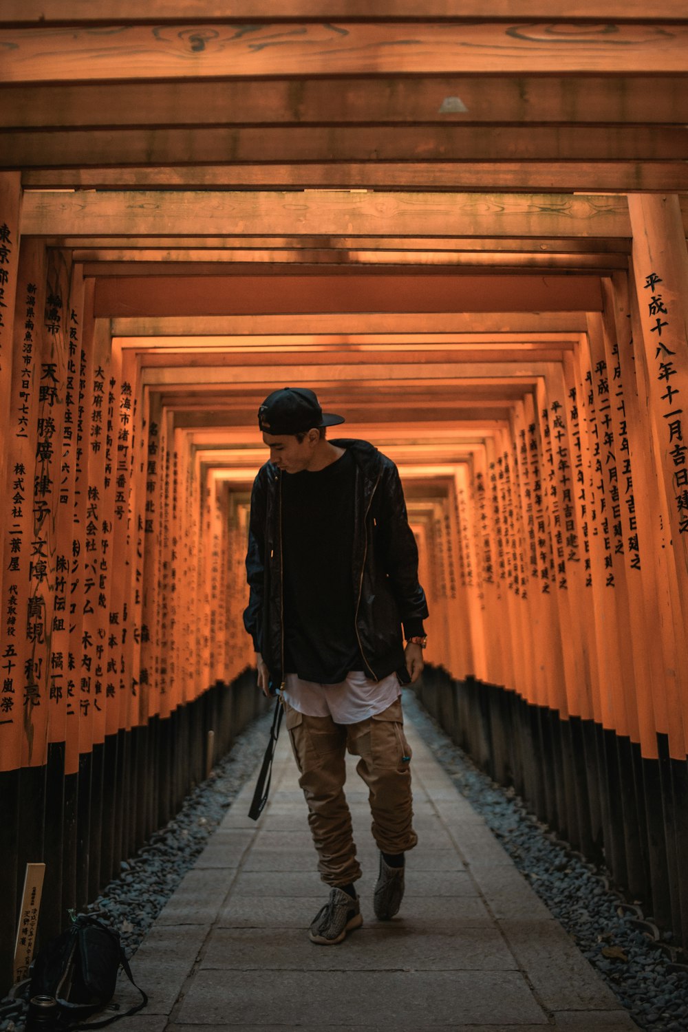 Homem de pé entre o portão de torii