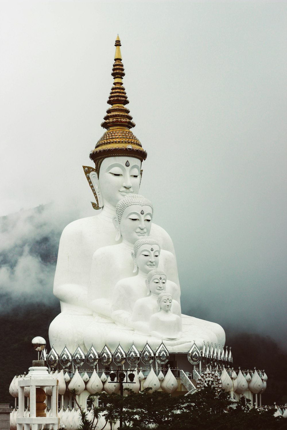several white buddha monument overlooking hill covered on fog at daytime