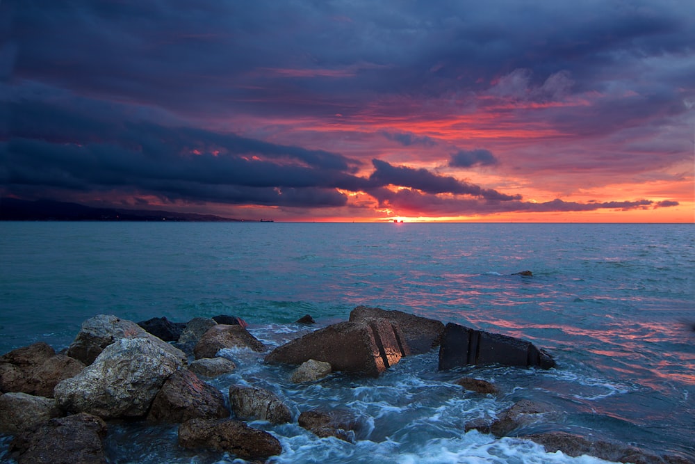 rock on ocean under cloudy sky at golden hour