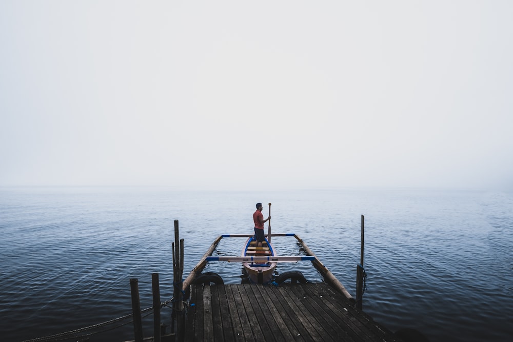Homme debout sur un canoë près du quai pendant la journée