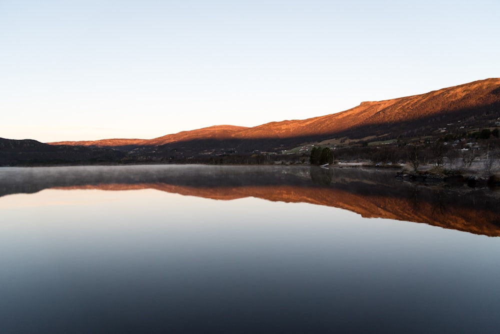 landscape photography of lake by the mountain under blue calm sky