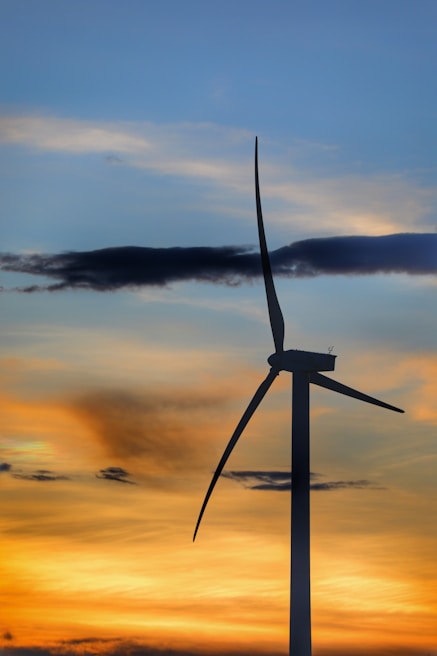 A close-up of a wind turbine spinning against a sunset.