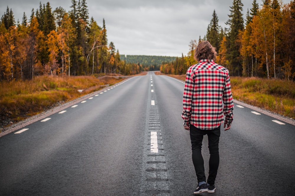 person standing on middle of blacktop road during daytime