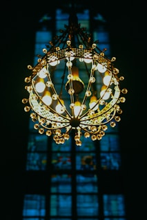 A technician fitting a glowing chandelier in a cozy living room, with warm light reflecting on the walls.
