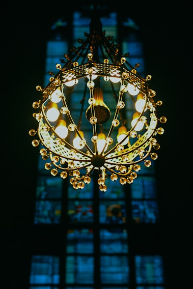 A technician fitting a glowing chandelier in a cozy living room, with warm light reflecting on the walls.