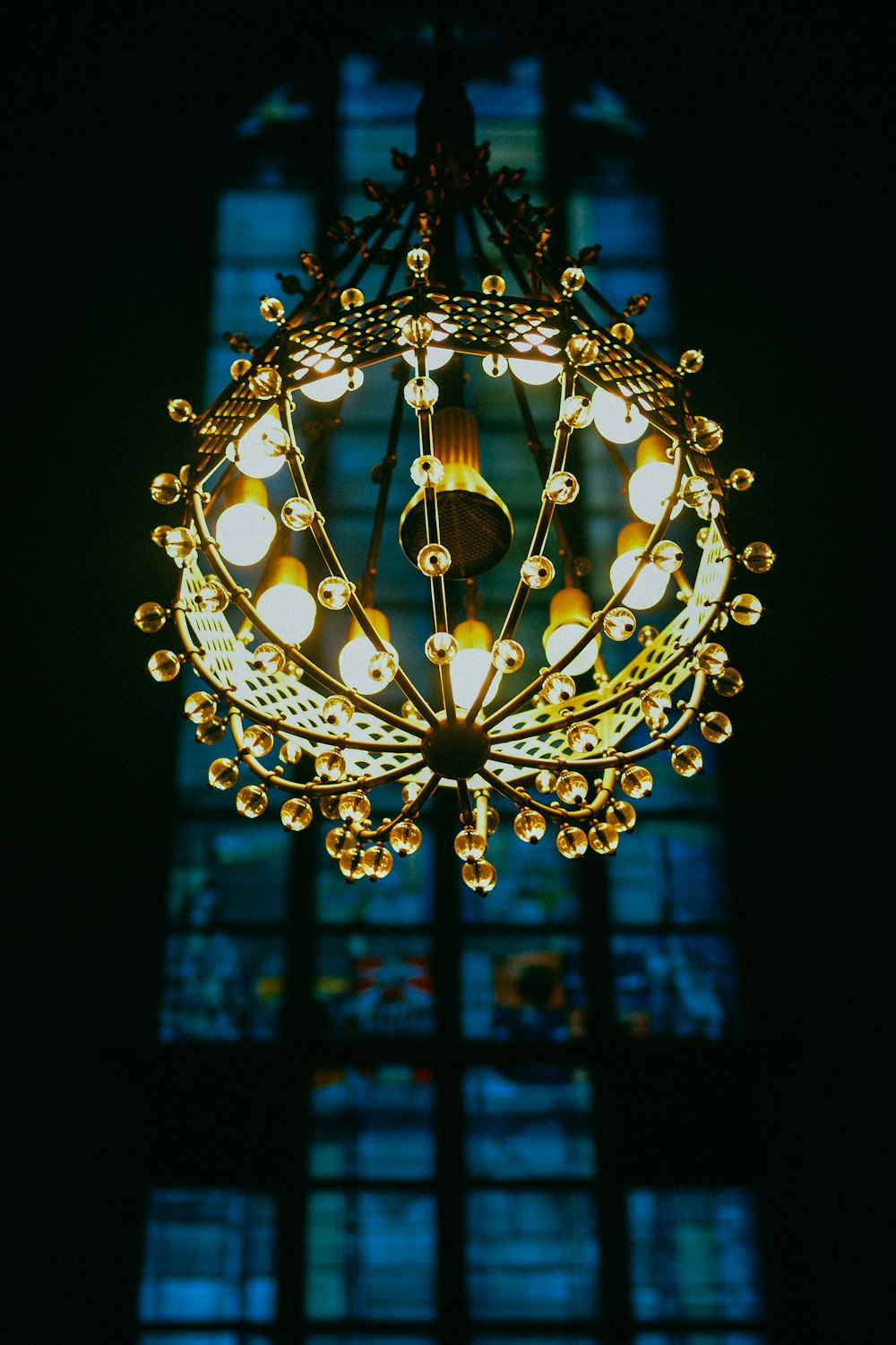 yellow lighted chandelier with stained glass window background