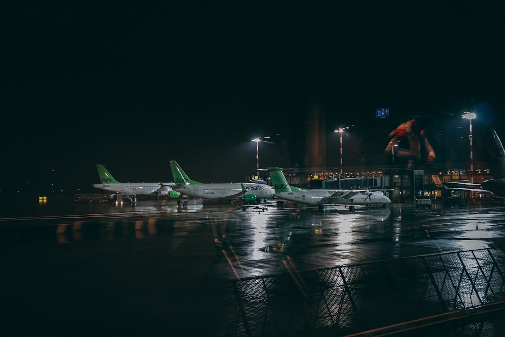 three white and green plane on the airport photography during nighttime