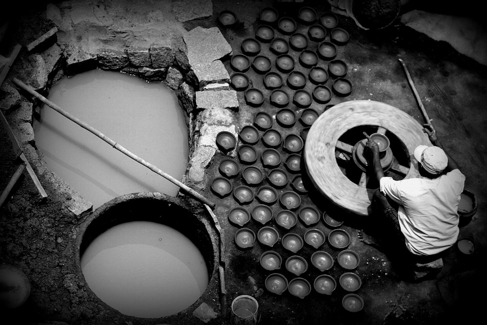 greyscale photography of man making clay bowls
