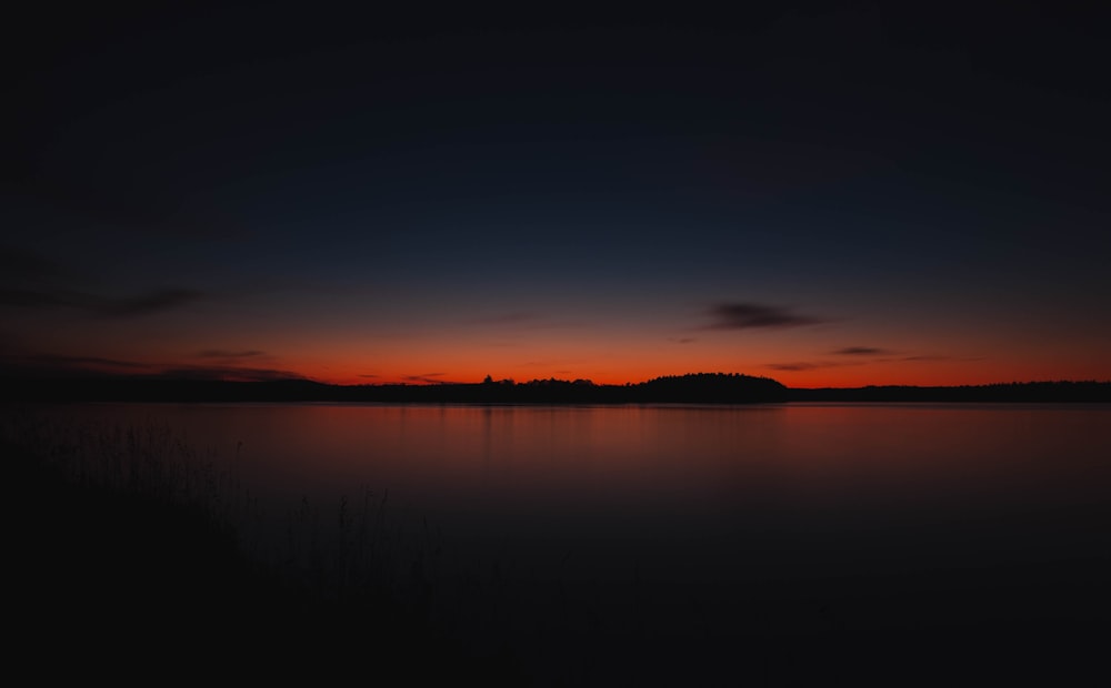 silhouette of mountains near body of water during golden hour