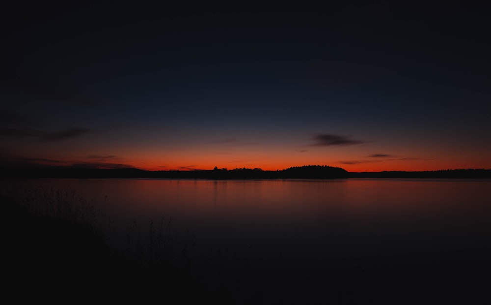 Silhouette von Bergen in der Nähe eines Gewässers während der goldenen Stunde