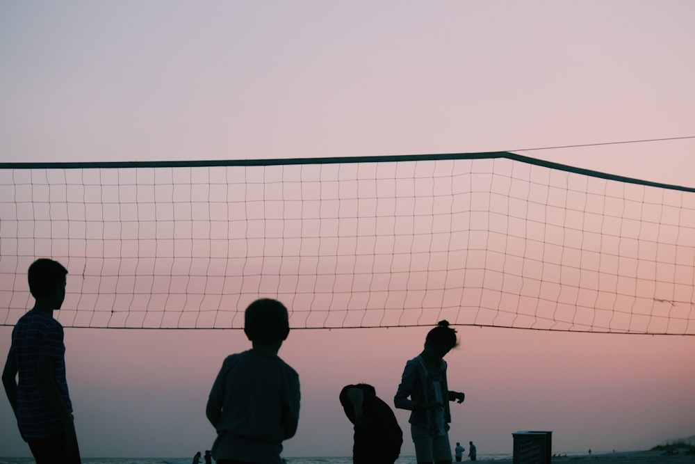 silhouette of four people playing volleyball during nighttime