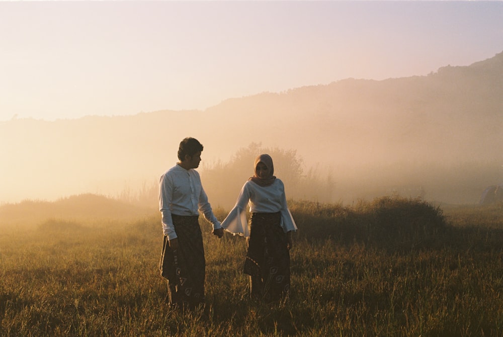 couple standing on grass field with fogs