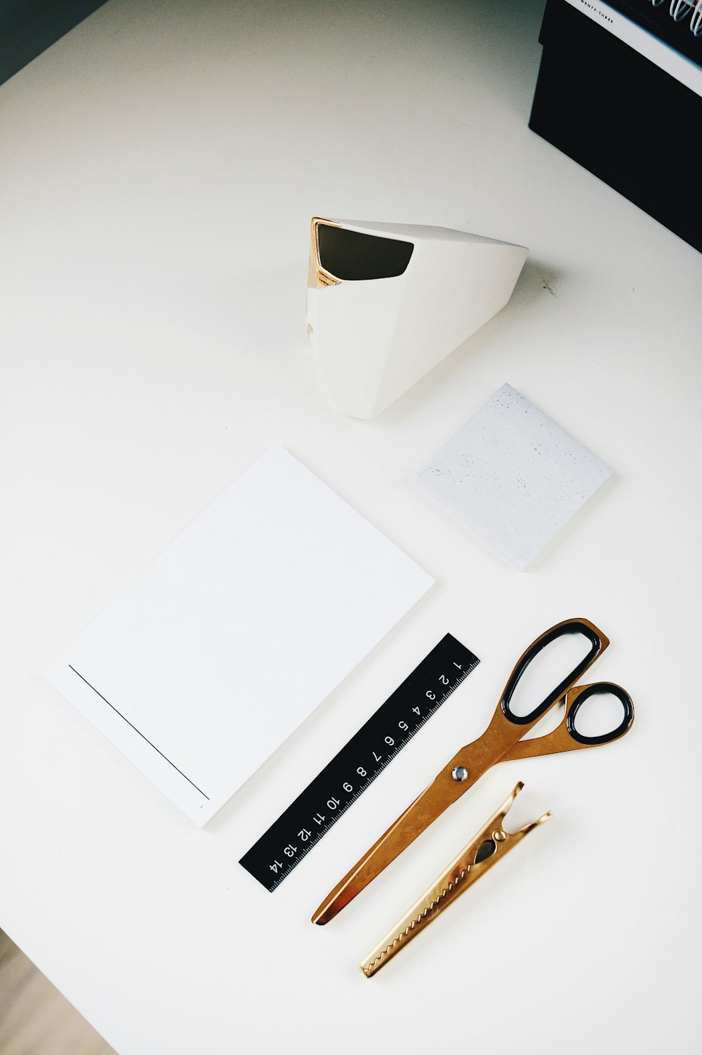 brown scissor beside clip and white printer paper on white surface