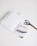 A neatly arranged set of office supplies including spiral notebooks, a binder clip, a pair of scissors, and a notebook with abstract art on the cover are placed on a clean white surface.