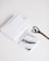 A neatly arranged set of office supplies including spiral notebooks, a binder clip, a pair of scissors, and a notebook with abstract art on the cover are placed on a clean white surface.