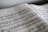 An open sheet music book displays musical notes and annotations written on the pages. The notes are clearly printed, and there are some handwritten marks or comments visible around the edges.