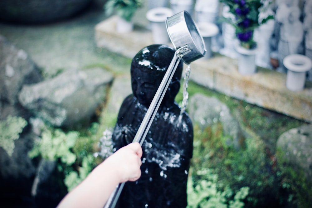 person watering figurine during daytime