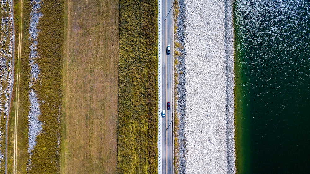 an aerial view of a road next to a body of water