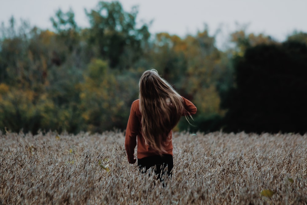 woman holding her hair standing at grass field