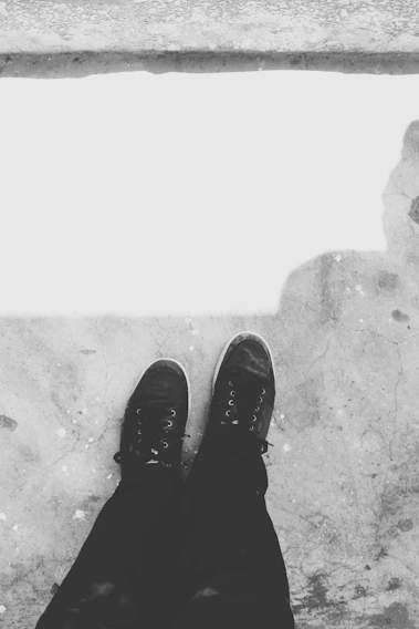 A sleek pair of black and white sneakers placed side by side on a minimalist concrete floor, highlighting the contrast and symmetry.
