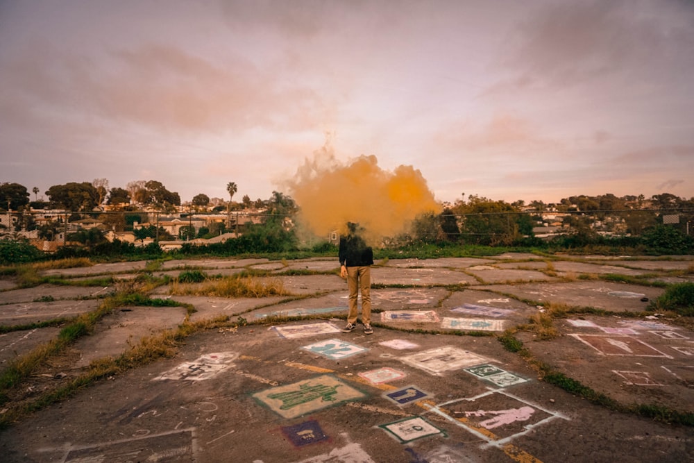 man standing surrounded by yellow smoke taken at daytime