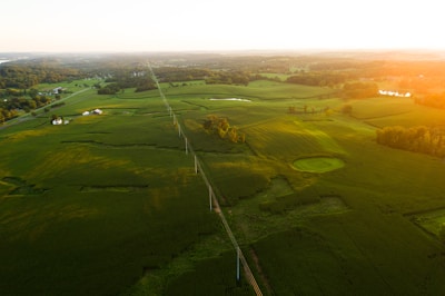 Aerial view of green land plots near a growing urban area at sunset.