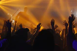 Audience enjoying a live concert with glowing orange lights.