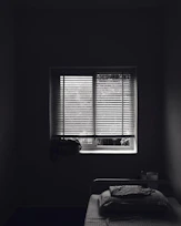 Simple non-AC room with neat bedding and a window letting in daylight.