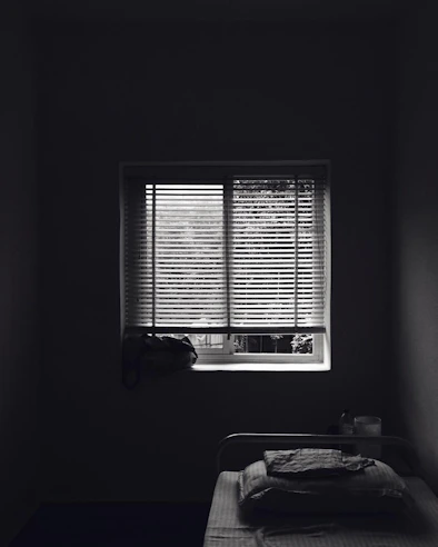 Simple non-AC room with neat bedding and a window letting in daylight.