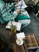 A candid shot of a teen girl journaling in a cozy café corner filled with plants.