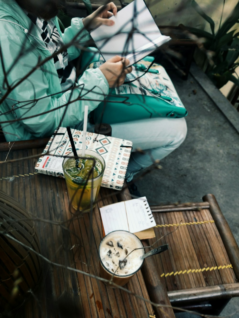 person sitting holding book beside brown wooden table