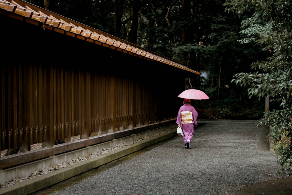 Geisha hält Regenschirm in der Nähe des Zauns