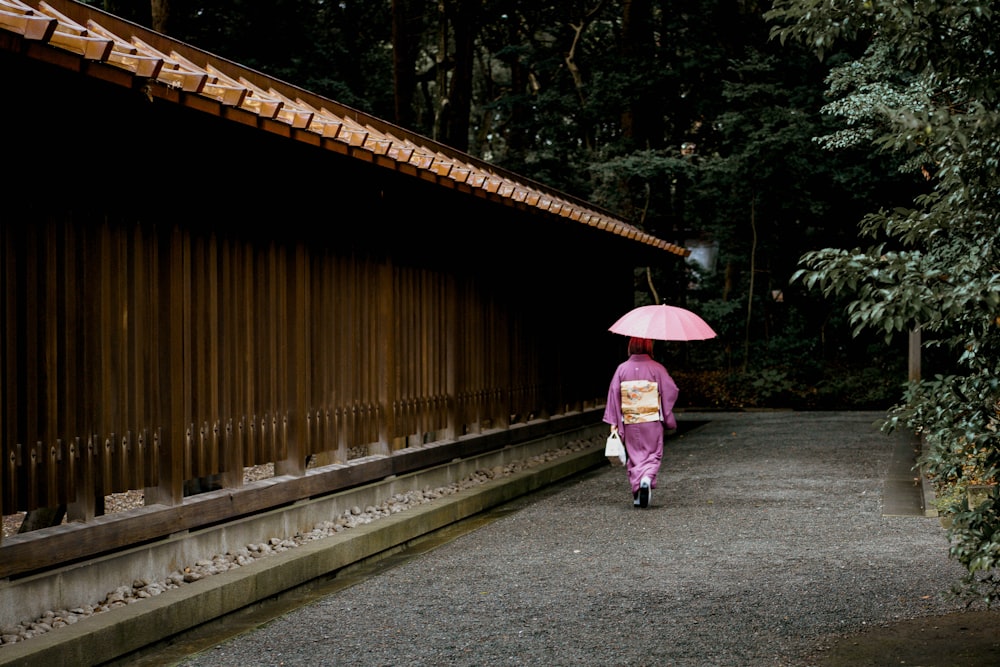 geisha che tiene l'ombrello vicino alla recinzione