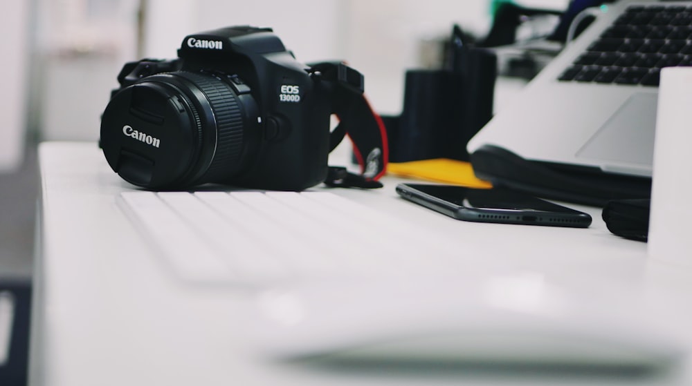 selective focus photography of DSLR camera beside keyboard