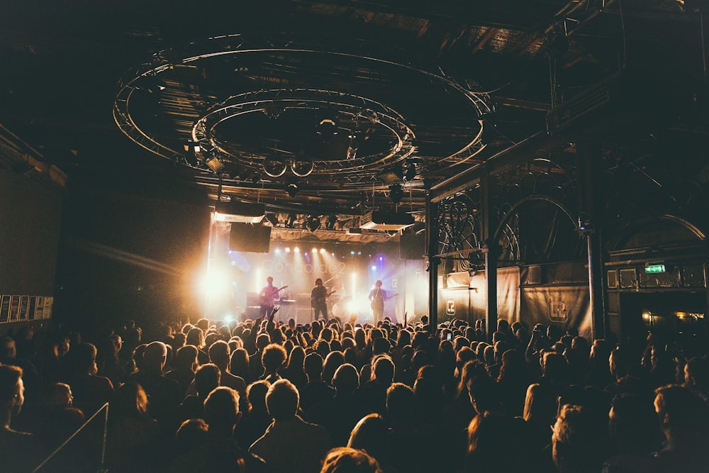 Personas que asisten a un concierto dentro de la sala oscura