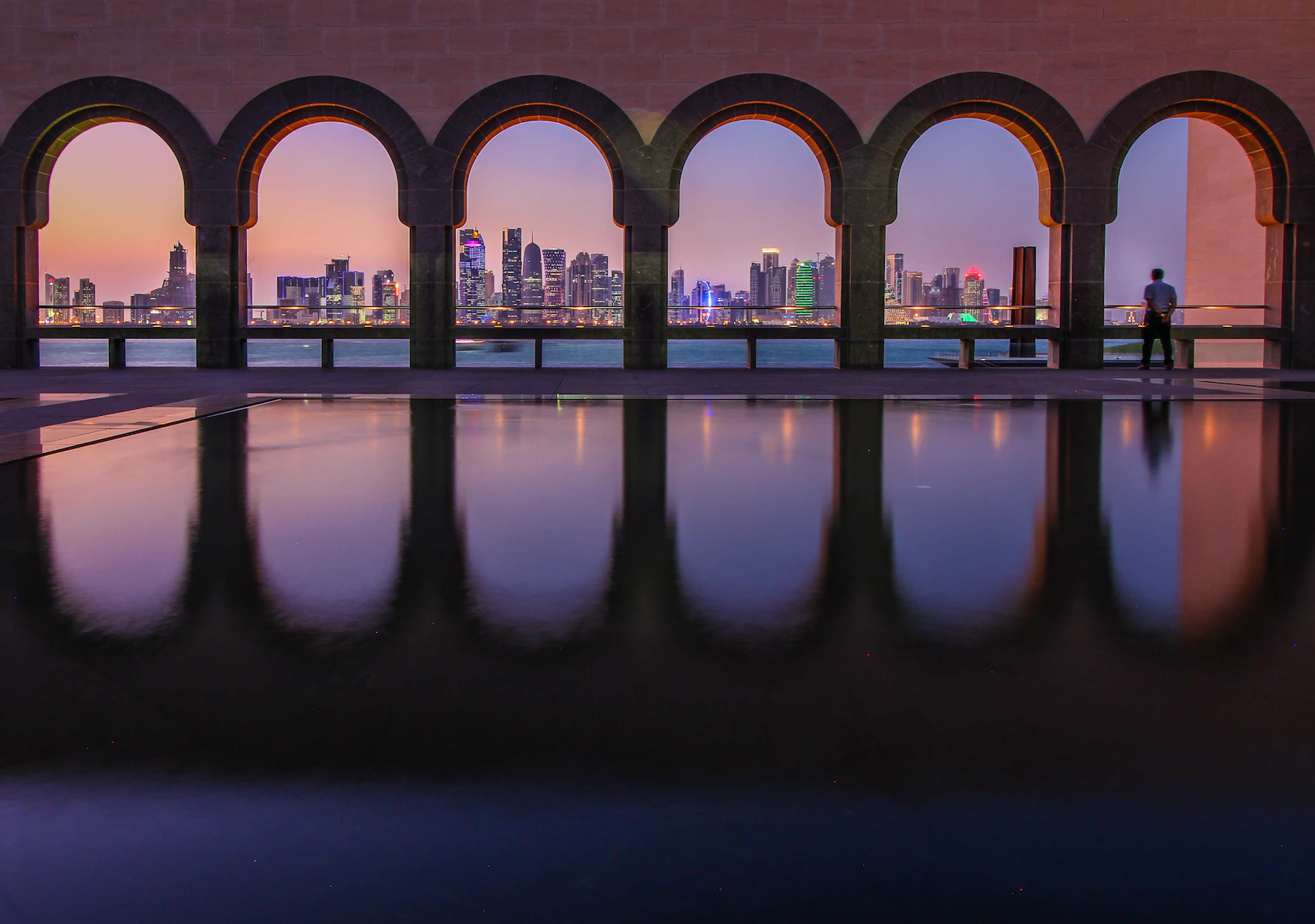 Doha's skyline framed by the arches of the Museum of Islamic Art at dusk