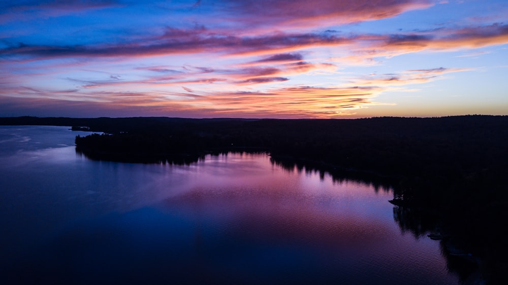 body of water near mountain during sunset