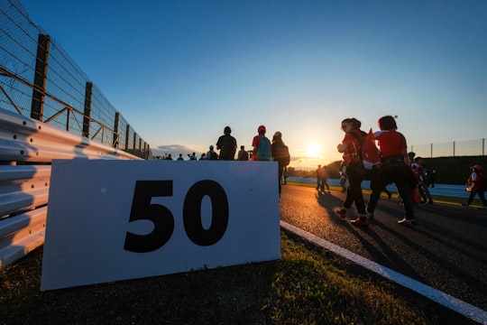 people walking on road beside white board with 50 text print in Suzuka Circuit Japan