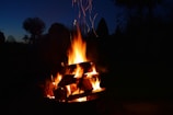 A rustic campfire glowing warmly under a starry night sky.