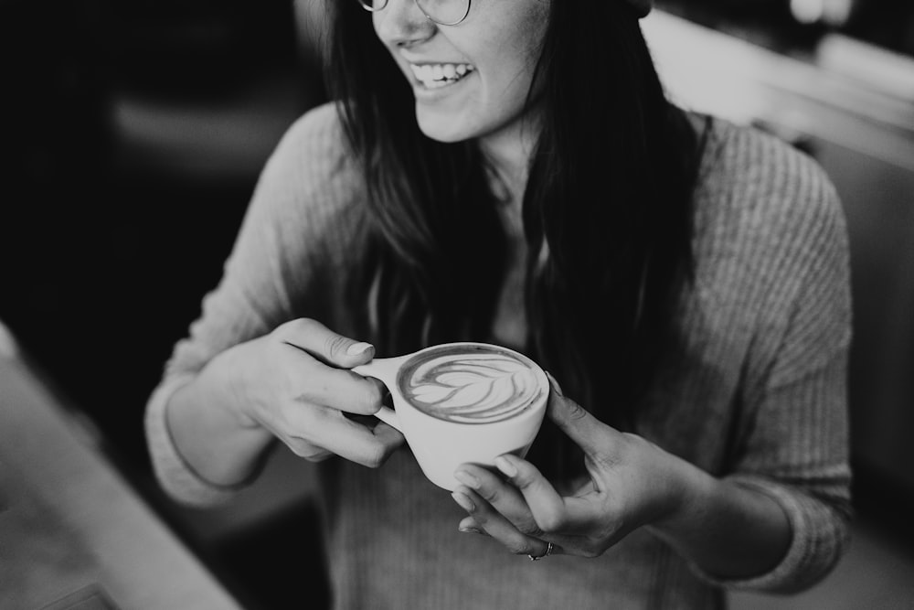 Foto en escala de grises de una mujer sosteniendo un café