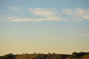 A minimalist landscape with gentle hills under a vast, pale sky.