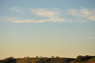 A minimalist landscape with gentle hills under a vast, pale sky.