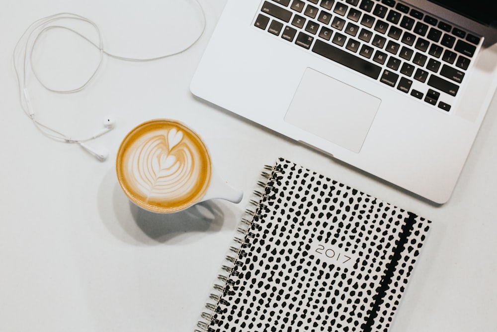 white ceramic mug beside laptop